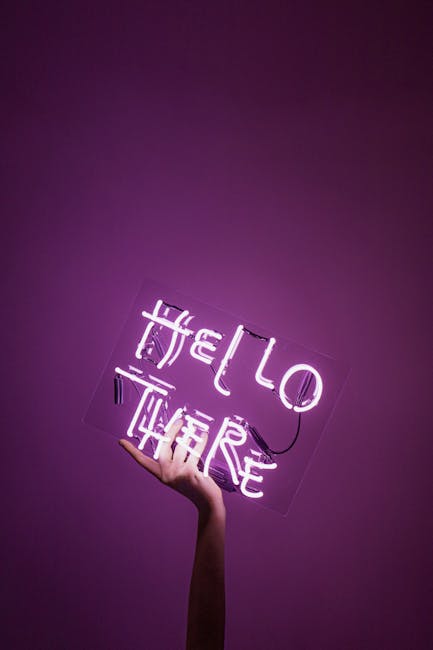 A hand holding a neon sign with the text 'Hello There' against a purple background, creating a vivid contrast.